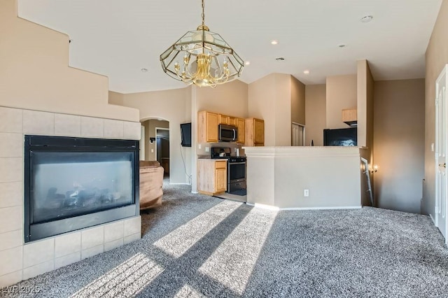 kitchen with carpet, black gas range oven, arched walkways, stainless steel microwave, and decorative light fixtures