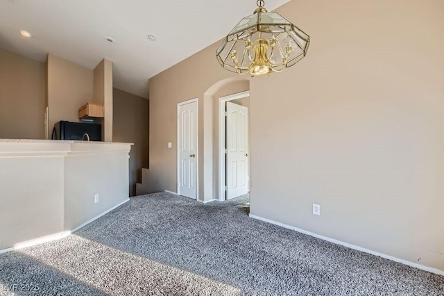 spare room with baseboards, carpet floors, lofted ceiling, and an inviting chandelier