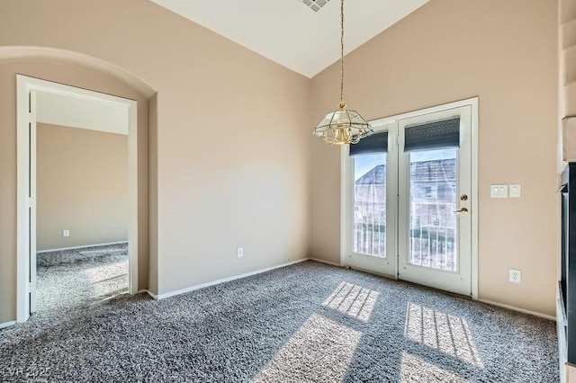 carpeted spare room featuring lofted ceiling, a notable chandelier, and baseboards