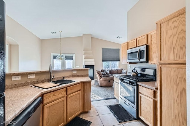 kitchen featuring light tile patterned floors, a sink, stainless steel appliances, vaulted ceiling, and open floor plan