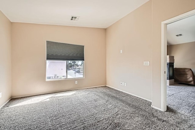 empty room featuring carpet, visible vents, and baseboards