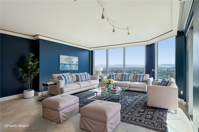 living room with a mountain view, rail lighting, light tile patterned flooring, and baseboards