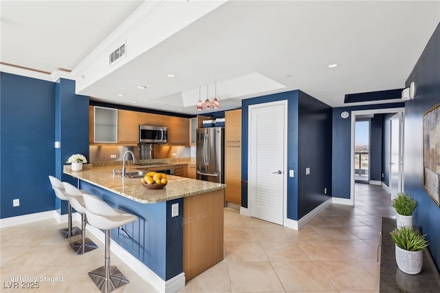 kitchen with light stone counters, visible vents, a peninsula, appliances with stainless steel finishes, and a kitchen breakfast bar