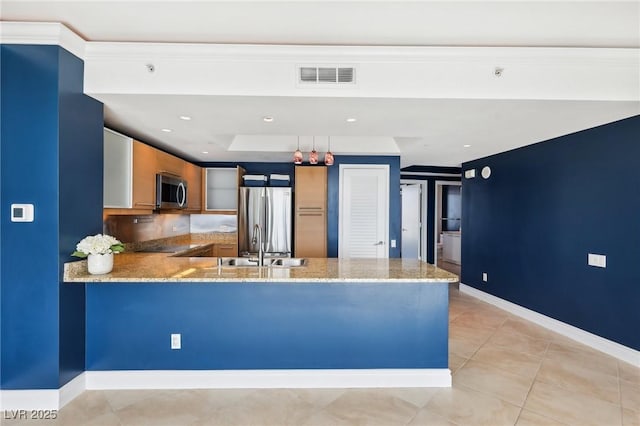 kitchen with light stone countertops, visible vents, a peninsula, a sink, and appliances with stainless steel finishes