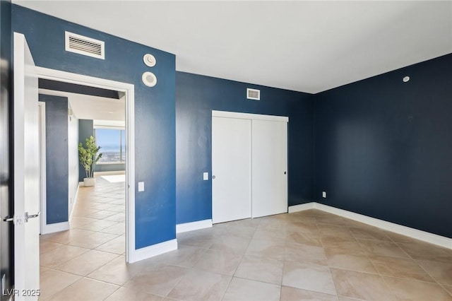 unfurnished bedroom with baseboards, visible vents, and a closet