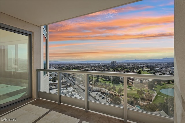 balcony at dusk featuring a city view and a mountain view