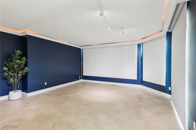 spare room featuring baseboards and track lighting