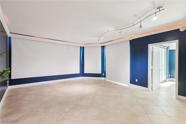 unfurnished room featuring rail lighting and baseboards