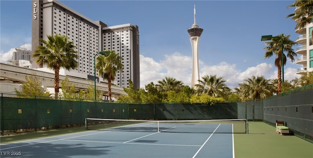 view of tennis court featuring a city view and fence