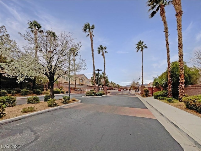 view of street with sidewalks, a gated entry, and curbs