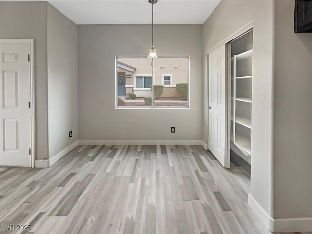 unfurnished dining area featuring baseboards and wood finished floors