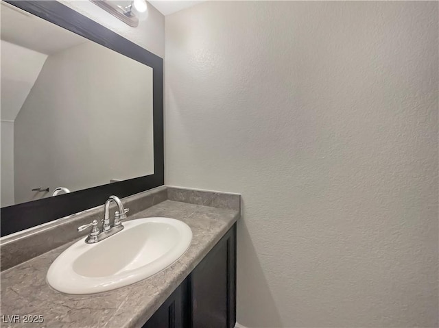 bathroom featuring a textured wall and vanity