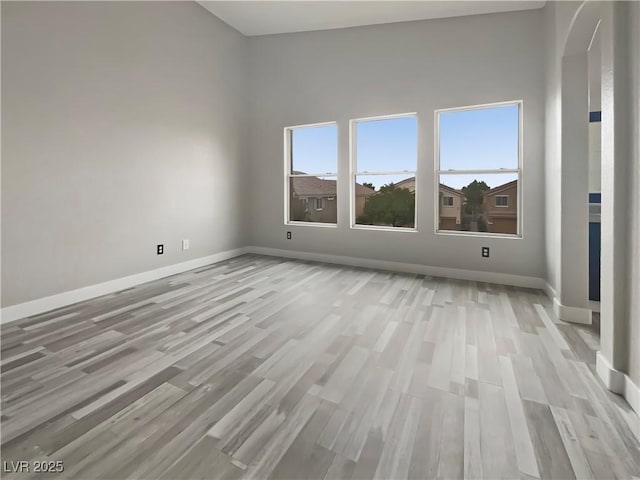 unfurnished room with light wood-type flooring, baseboards, and a wealth of natural light