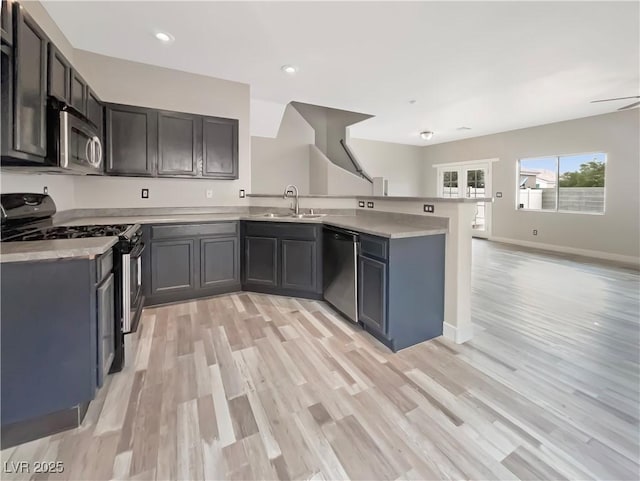 kitchen with a sink, a peninsula, appliances with stainless steel finishes, and light countertops