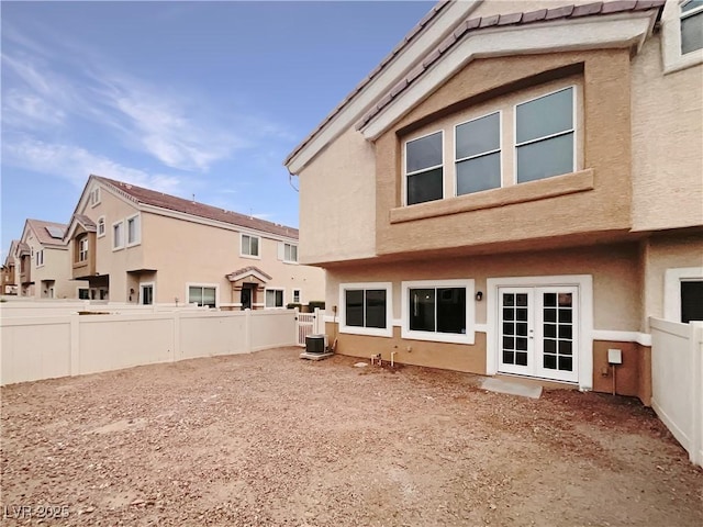 back of property with french doors, a fenced backyard, central AC, and stucco siding