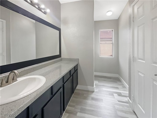 bathroom featuring vanity, baseboards, and wood finished floors