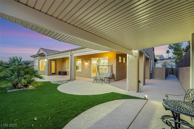 patio terrace at dusk with a yard and fence