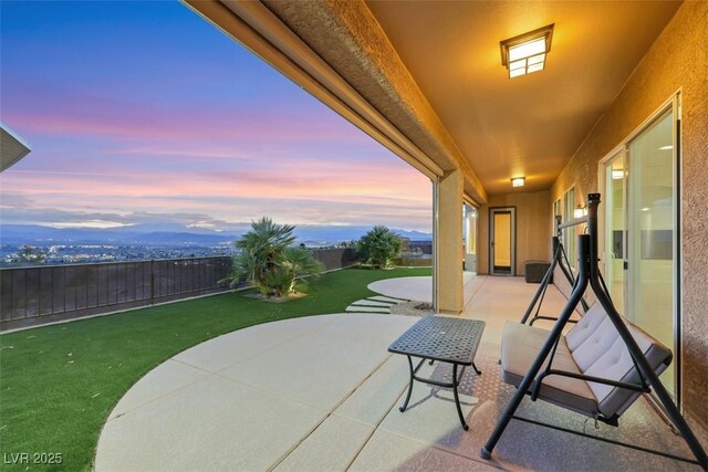 patio terrace at dusk with a lawn and fence