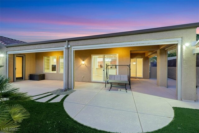 rear view of house featuring a patio and stucco siding