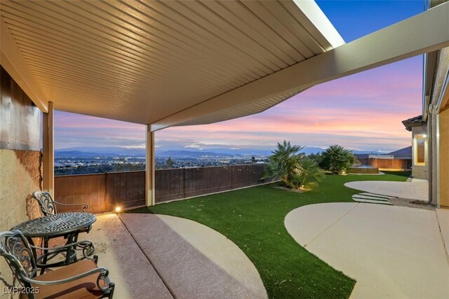 yard at dusk with a patio and a fenced backyard