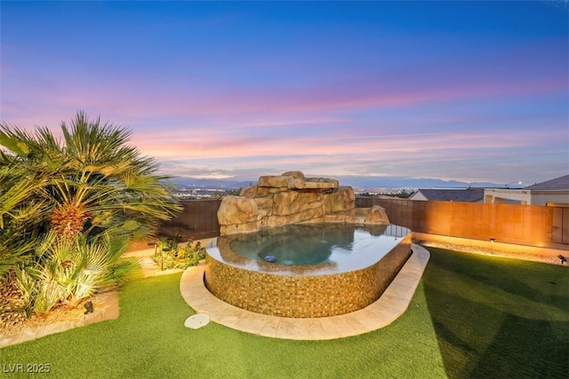 pool at dusk with a fenced backyard