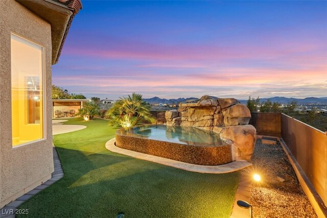 view of yard featuring an in ground hot tub, a fenced backyard, and a mountain view