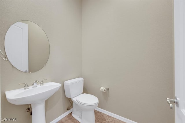 half bathroom with tile patterned floors, toilet, baseboards, and a sink