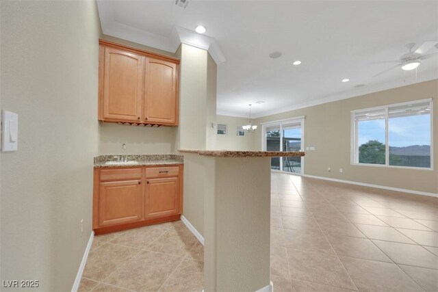 kitchen with light stone counters, baseboards, ornamental molding, and light tile patterned floors