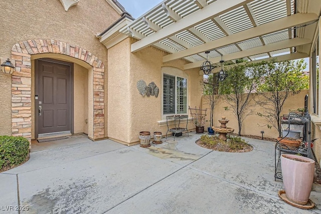 entrance to property featuring fence, a pergola, a patio, and stucco siding