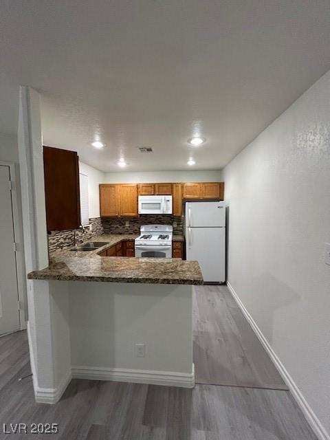 5044 S Rainbow Blvd Unit 106, Las Vegas, NV 89118 - kitchen with a sink, white appliances, light wood finished floors, backsplash, and a peninsula