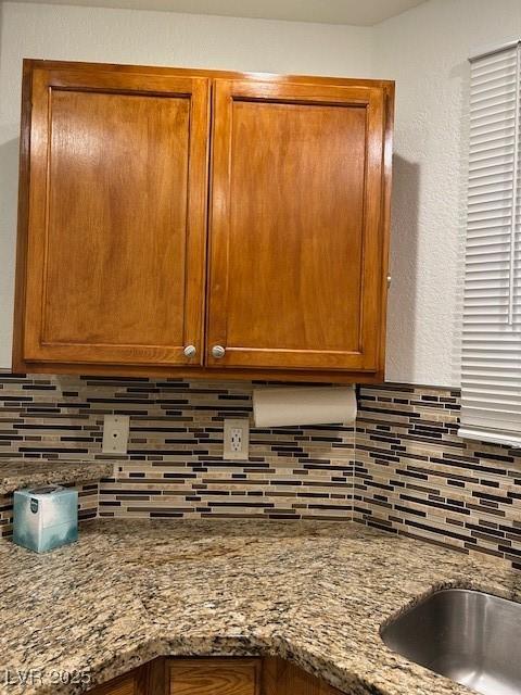5044 S Rainbow Blvd Unit 106, Las Vegas, NV 89118 - details with backsplash, brown cabinets, stone countertops, and a sink