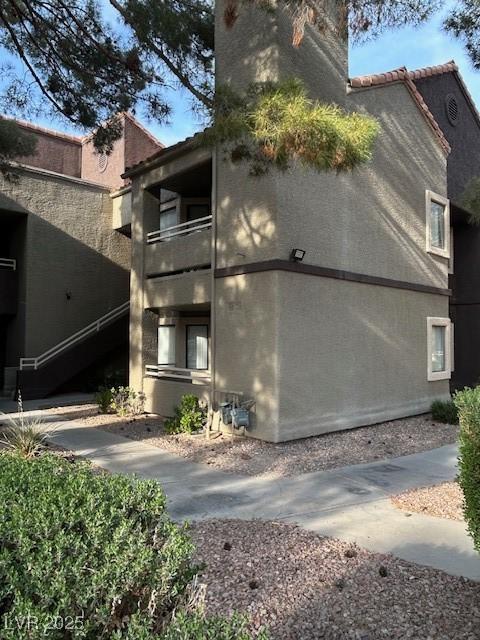 5044 S Rainbow Blvd Unit 106, Las Vegas, NV 89118 - view of side of home featuring stucco siding, a balcony, and a tiled roof