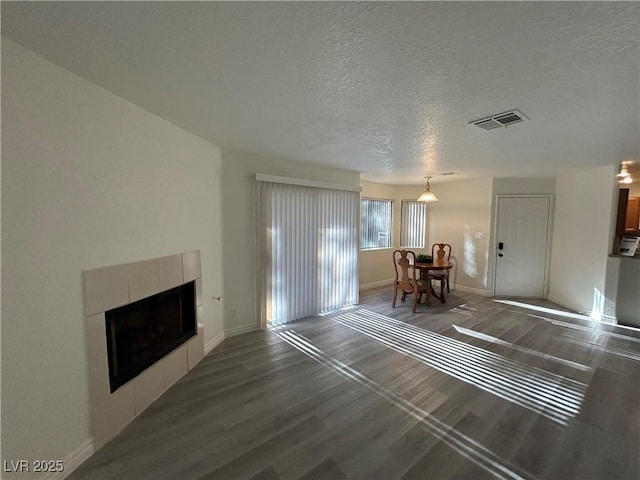 5044 S Rainbow Blvd Unit 106, Las Vegas, NV 89118 - living area featuring baseboards, dark wood-type flooring, visible vents, and a tiled fireplace