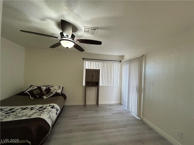 5044 S Rainbow Blvd Unit 106, Las Vegas, NV 89118 - bedroom featuring visible vents, baseboards, light wood-style flooring, a textured ceiling, and ceiling fan