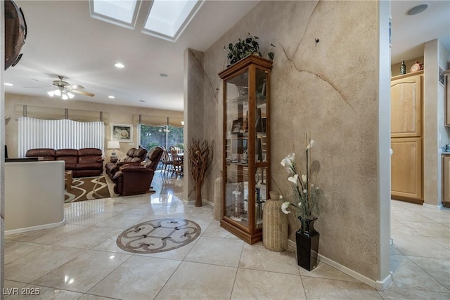 foyer with a skylight, ceiling fan, baseboards, and recessed lighting