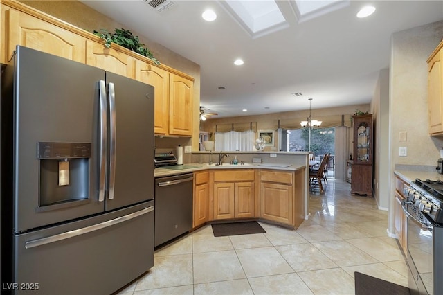 kitchen with a peninsula, stainless steel appliances, light countertops, a sink, and recessed lighting