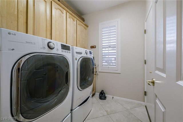 laundry area featuring light tile patterned floors, washing machine and clothes dryer, cabinet space, and baseboards