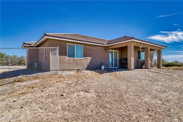 rear view of property featuring fence and stucco siding