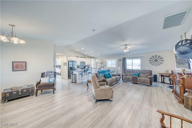 living area featuring vaulted ceiling, light wood finished floors, visible vents, and a notable chandelier