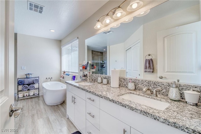 full bath with double vanity, a stall shower, visible vents, and a sink