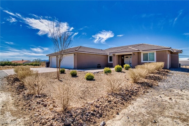 ranch-style home with driveway, fence, an attached garage, and stucco siding