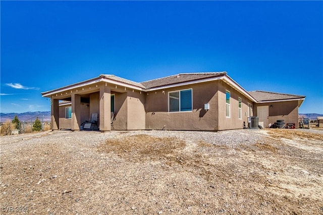 view of front of home with a mountain view, cooling unit, and stucco siding