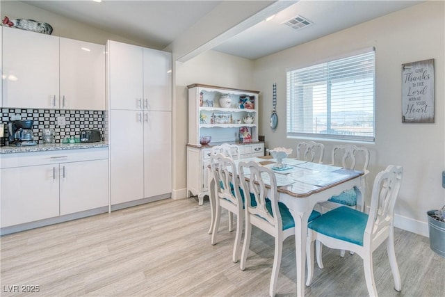 dining room featuring light wood-style floors, baseboards, and visible vents