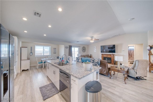 kitchen with stainless steel dishwasher, a center island with sink, a sink, and visible vents