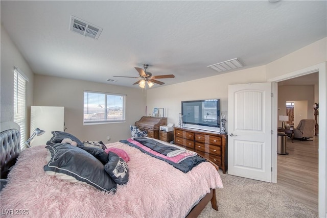 bedroom featuring a ceiling fan, light colored carpet, and visible vents