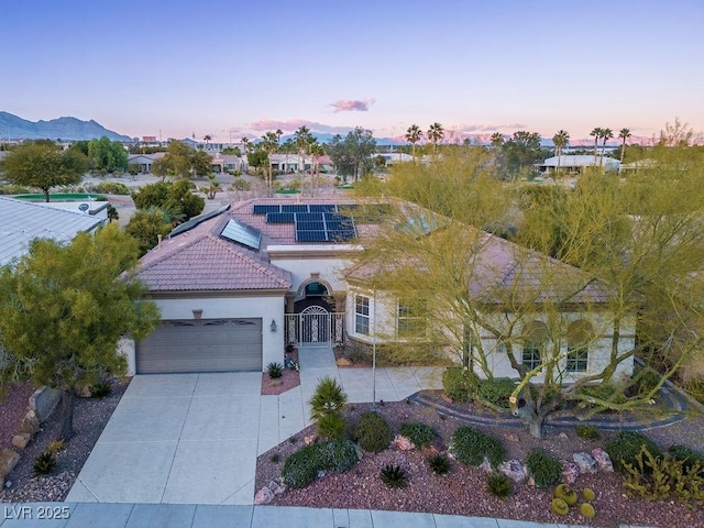 view of front of home with a tile roof, stucco siding, an attached garage, a gate, and driveway