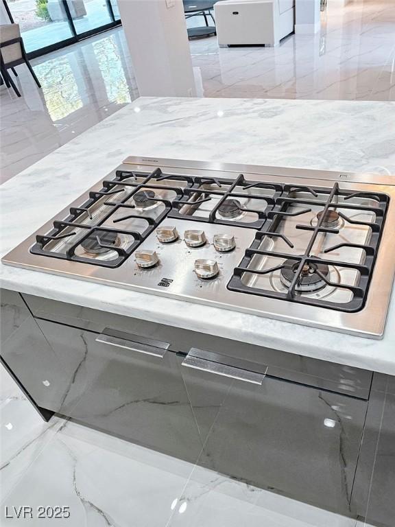 interior details featuring light stone countertops and stainless steel gas stovetop