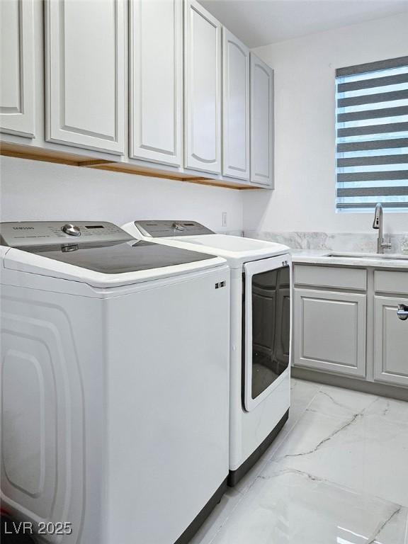 clothes washing area with marble finish floor, washing machine and dryer, cabinet space, and a sink