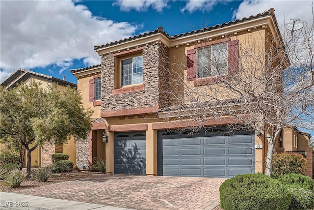 view of front of property featuring stucco siding, a tile roof, decorative driveway, stone siding, and a garage