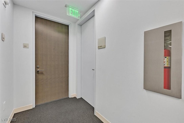 corridor featuring baseboards and carpet flooring